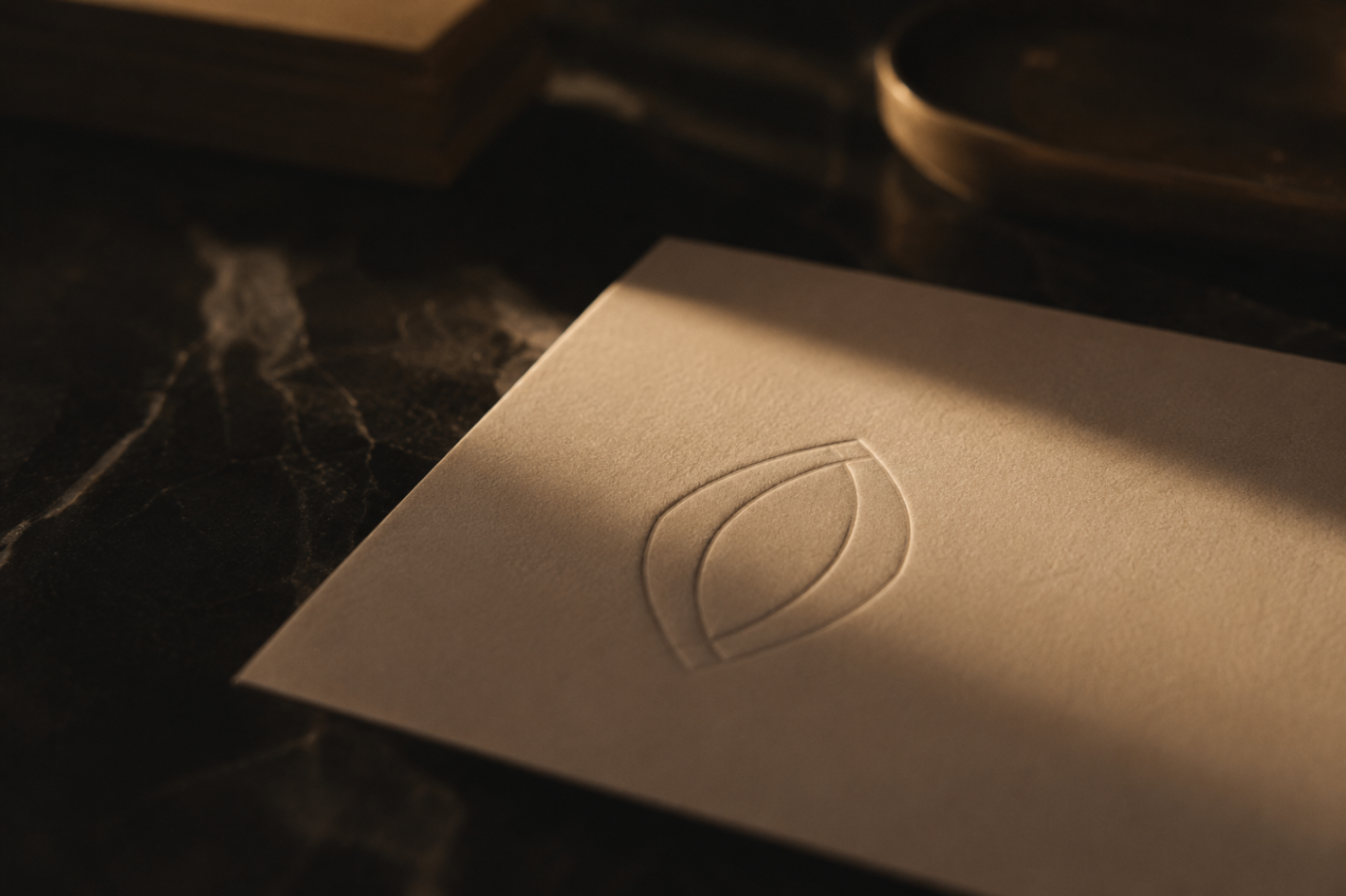 A blind-embossed pointed-oval emblem on a heavy ivory invitation card.